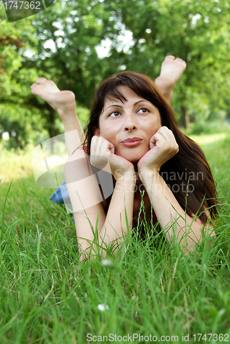 Image of Woman portrait lying in grass dreaming