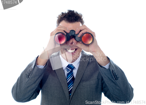 Image of Smiling businessman looks through binoculars