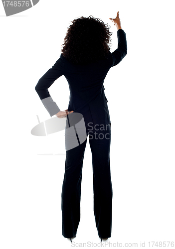 Image of Rear view of female pointing at copy space