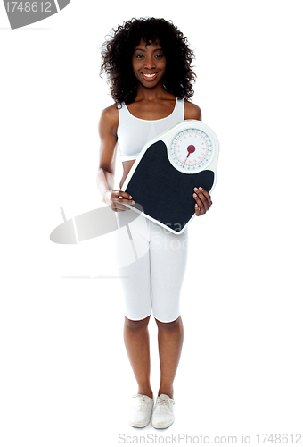 Image of Fit female athlete holding weighing machine