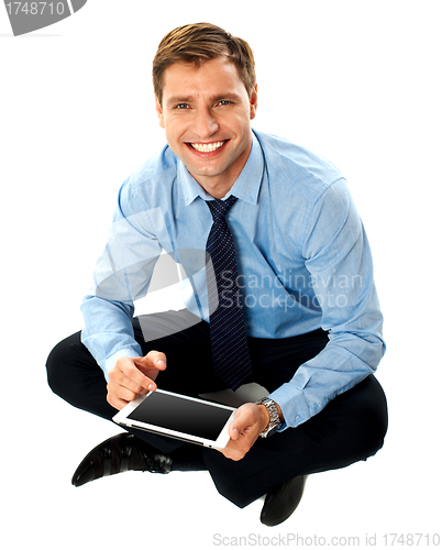 Image of Man sitting on floor using touch screen device
