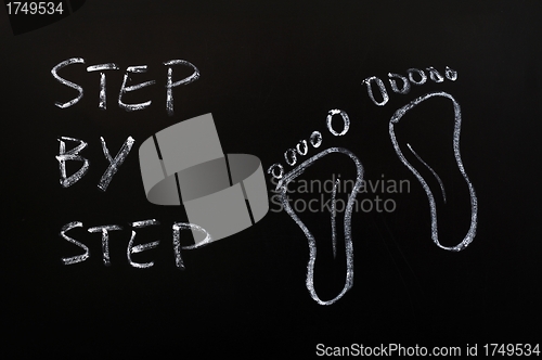 Image of Footprints and the words step by step drawn with chalk