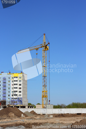 Image of yellow crane and blue sky on building site