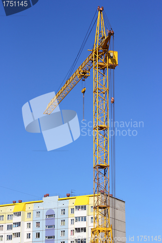 Image of yellow crane and blue sky on building site