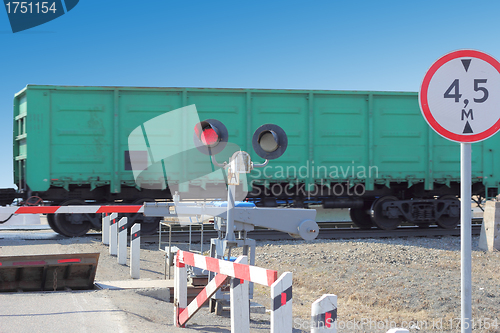 Image of railroad cars at the crossing with a barrier 
