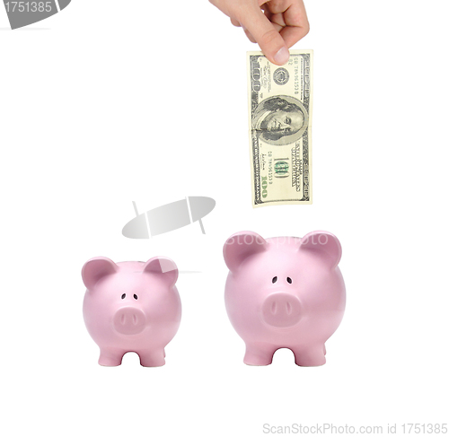 Image of hand putting dollar bills into a pink piggy bank