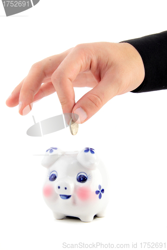 Image of Hand inserting coin into piggy-bank