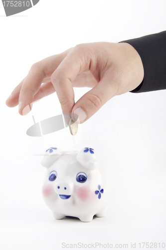 Image of Hand inserting coin into piggy-bank