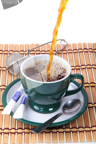 Image of Pouring fresh tea into green cup