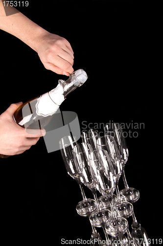 Image of man hands opening champagne bottle