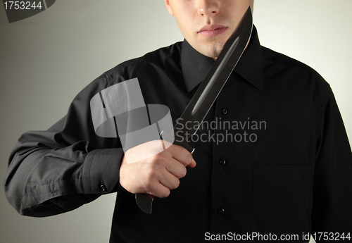 Image of standing man in black with knife