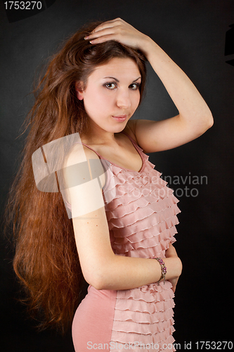 Image of Woman in a pink dress posing on a black background.