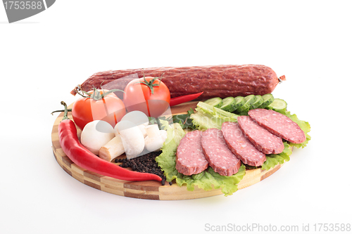 Image of sliced sausage with vegetables on board