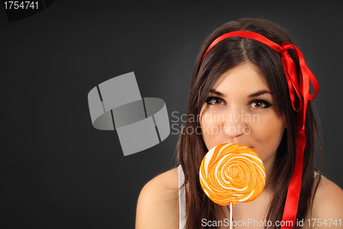 Image of pretty happy curly girl with a lollipop in her hand