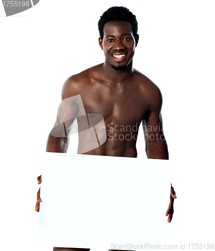 Image of Young muscular man holding blank billboard