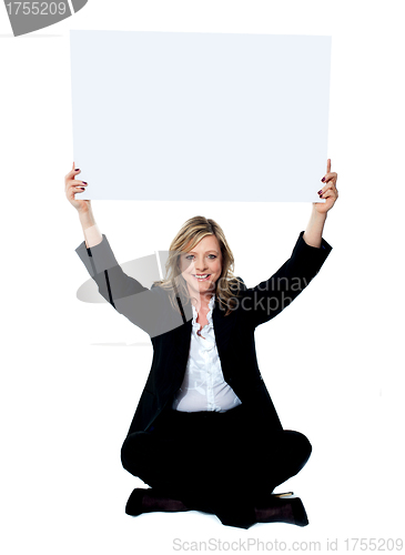 Image of Seated female employee holding white clipboard over her head