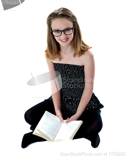 Image of School girl sitting on floor holding book
