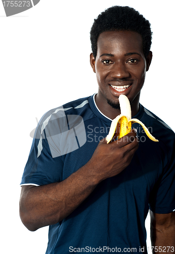 Image of Young fit guy eating banana