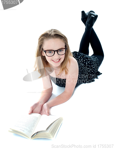 Image of Smiling little girl lying with an open book