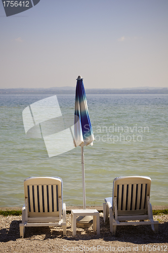 Image of Beach chairs and closed umbrella on the beach