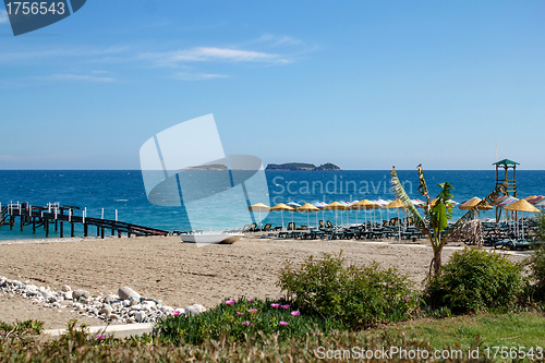 Image of beach with pier and umbrellas