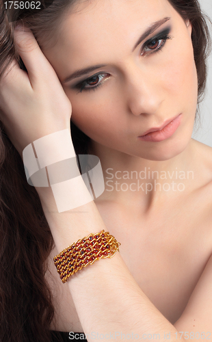 Image of beautiful girl straightens her hair with bracelet on her arm