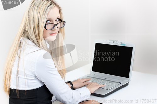 Image of Woman sitting on workplace with laptop in office