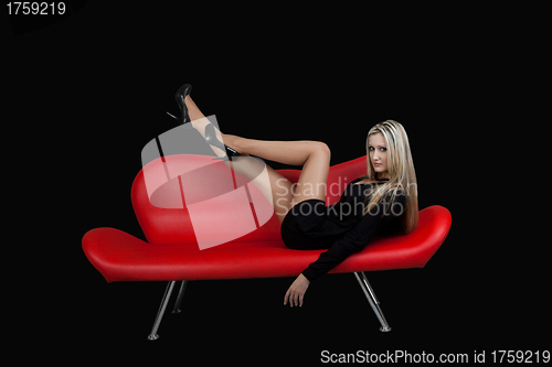 Image of Sexual blonde in black dress on red couch. black background