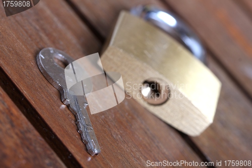 Image of padlock with key on wooden background