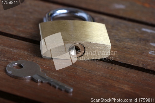 Image of padlock with key on wooden background