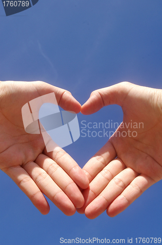 Image of Man hands forming a heart over the blue sky 