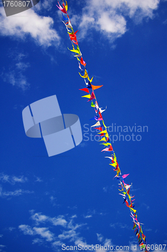 Image of Multi colored party flags on a line on a background of blue sky 