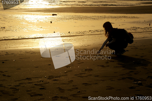 Image of Girl drawing on sand at sunset