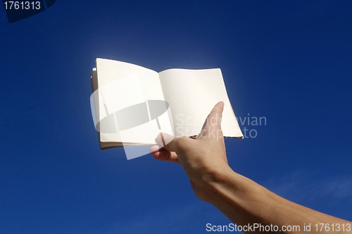 Image of Holding notebook under blue sky