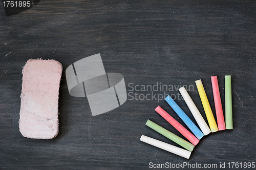 Image of Colorful chalk and eraser on a blank smudged blackboard