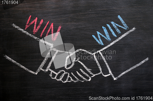 Image of Mutual benefit concept of handshaking on blackboard