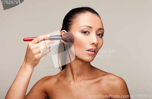 Image of Young beautiful woman applying makeup