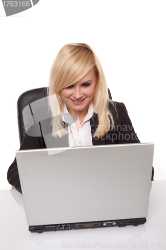 Image of Efficient blonde businesswoman working on her laptop with her spectacles on the table alongside her