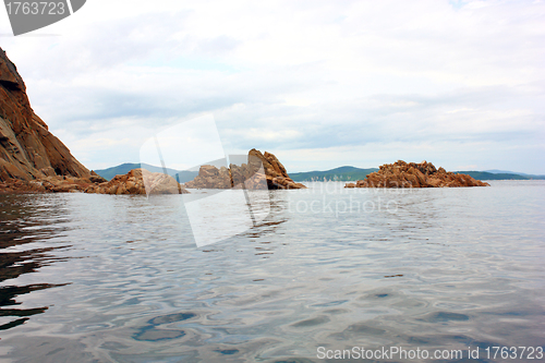 Image of Rocks in the blue sea, illuminated by the sun. Background.