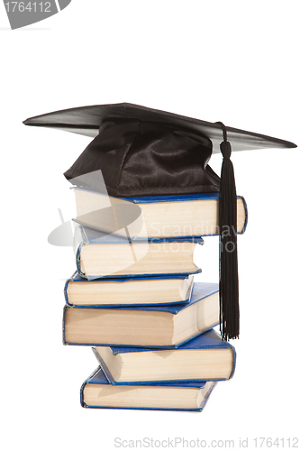 Image of books with black cap of bachelor isolated on white