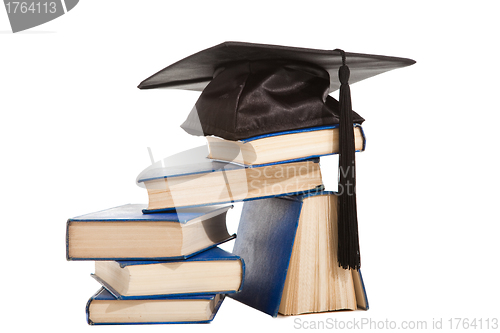 Image of books with black cap of bachelor isolated on white