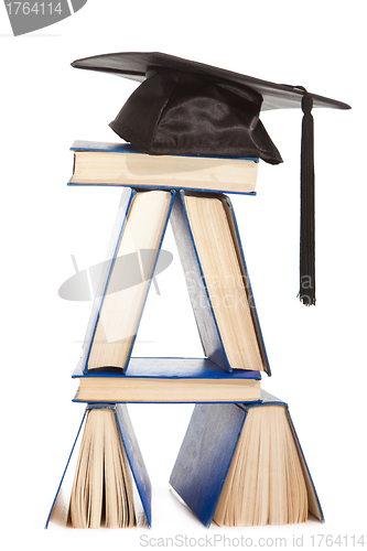 Image of books with black cap of bachelor isolated on white