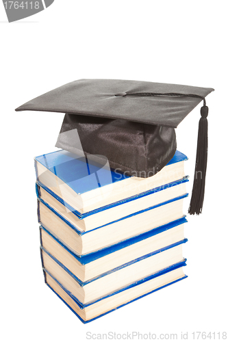 Image of books with black cap of bachelor isolated on white