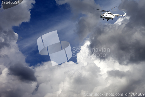 Image of Helicopter in blue sky with clouds