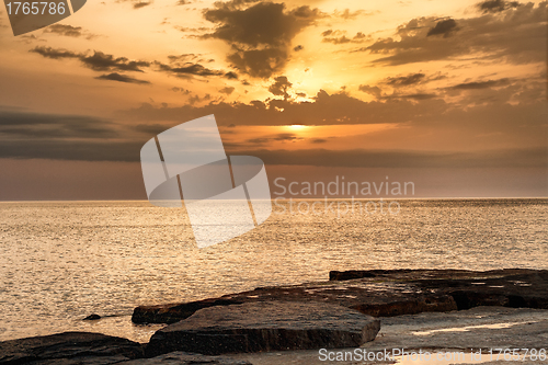 Image of Sun going down over  water glowing on the shore