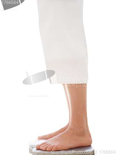 Image of Bare female feet standing on bathroom scale