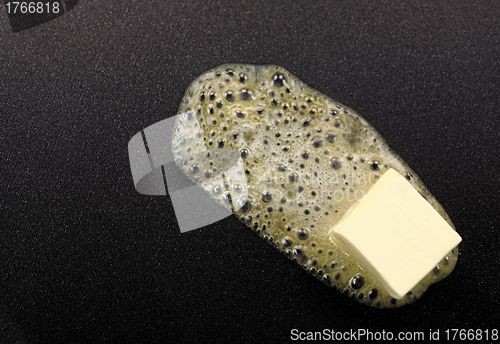 Image of Piece of butter melting on non-stick frying pan