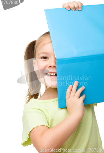 Image of Cute little girl is hiding behind a book