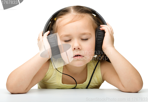 Image of Cute little girl enjoying music using headphones