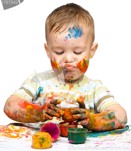 Image of Little boy is playing with paints